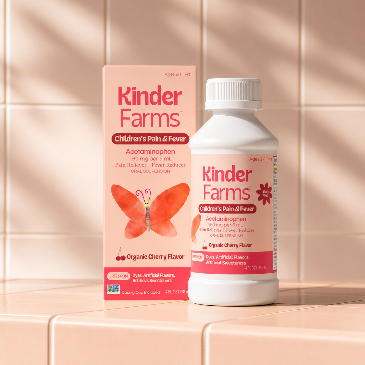 Kinder Farms Children's Pain and Fever medicine bottle and box shown against a light peach tiled wall. It is an acetaminophen-based oral suspension with organic cherry flavor.