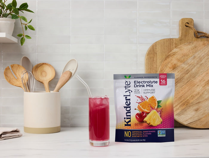 KindlerLyte electrolyte drink mix package with a glass of pink drink on a kitchen counter.