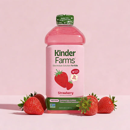 A bottle of Kinder Farms Strawberry Electrolyte Solution for Kids surrounded by fresh strawberries against a pink background.