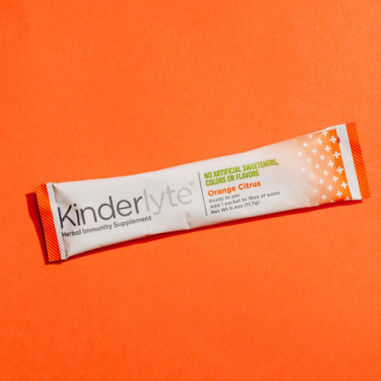 KinderLyte Powder packet on an orange background.